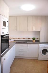 a kitchen with white cabinets and a washer and dryer at Brisa Mar in Málaga
