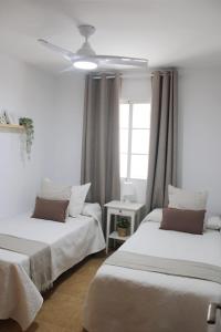 a bedroom with two beds and a ceiling fan at Brisa Mar in Málaga