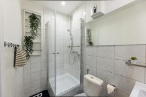 a white bathroom with a shower and a toilet at The Harbour Apartment 2 in Hamburg