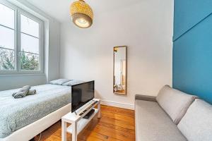 ein Schlafzimmer mit einem Bett, einem TV und einem Sofa in der Unterkunft Le Bon Pasteur-cosy 2 pers- Croix Rousse in Lyon