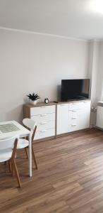 een woonkamer met een witte tafel en een tv bij Apartament przy Starym Mieście in Elblag