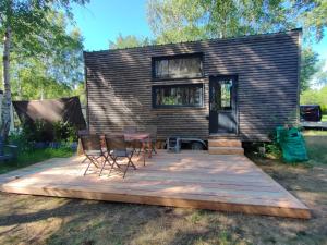 a tiny house with a wooden deck and chairs at Tiny house ocean in Naujac-sur-Mer