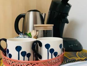 two mugs in a basket with a coffee maker at Chambre d hôte Entre Cigale et Pagnol in Peypin