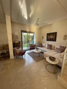 una sala de estar con un sofá blanco y mesas. en BEAU TRIPLEX EN RESIDENCE, en Skhirat