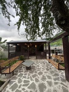 ein Pavillon mit Bänken und einem Tisch unter einem Baum in der Unterkunft Mestia Views in Mestia