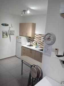 een keuken met een koelkast en een klok aan de muur bij Mikis Studio Type Aprt. in Larnaka