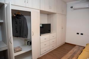 Finca Mosso Lunlunta في Lunlunta: غرفة نوم بها دواليب بيضاء وتلفزيون وخزانة