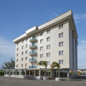 a large white building with palm trees in front of it at Simon Hotel in Pomezia