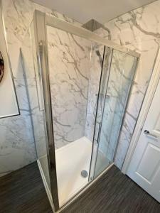 a shower in a bathroom with marble walls at Storey Apartment - 2 Bedroom upstairs flat in Newbiggin-by-the-Sea