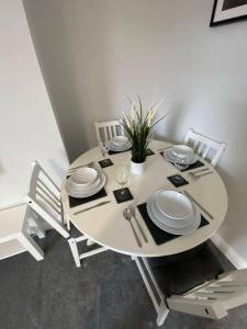 a white table with plates and utensils on it at Storey Apartment - 2 Bedroom upstairs flat in Newbiggin-by-the-Sea