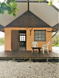 ファカラヴァ環礁にあるFAKARAVA - Teariki Lodge 2のデッキに椅子2脚とテーブル1台が備わる家
