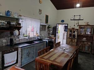 乌巴图巴Hostel e Hospedaria Familiar Artesanal的厨房配有带椅子的木桌和桌子。