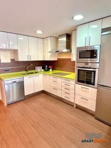 a kitchen with white cabinets and stainless steel appliances at APARTBEACH EUROPEOS JUNTO PLAYA CLIMATIZADO CON GRAN TERRAZA y MUY LUMINOSO in La Pineda