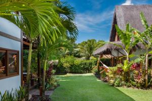 a garden with palm trees and a building at Aldeia dos Corais - Taipu de Fora in Barra Grande