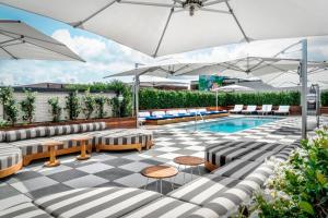 une piscine avec des parasols et des chaises ainsi qu'un patio dans l'établissement Perry Lane Hotel, a Luxury Collection Hotel, Savannah, à Savannah