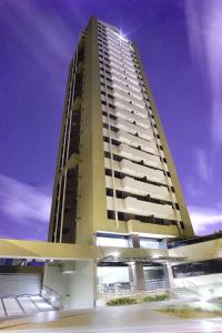 a tall apartment building with a purple sky at CJC Short Stay Natal in Natal