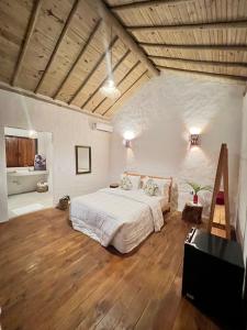 1 dormitorio con 1 cama blanca grande y suelo de madera en Villa Sagui Trancoso, en Trancoso