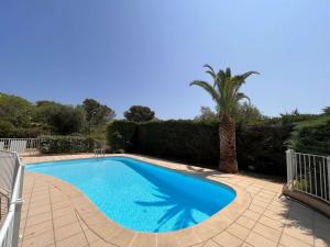 a blue swimming pool with a palm tree and a fence at Charmant T2/Mezzanine avec Piscine et Terrasse, à 5 min de la Plage, St-Raphaël - FR-1-226A-148 in Boulouris-sur-Mer