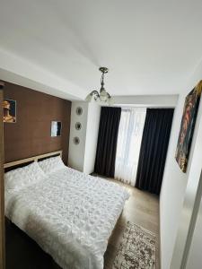 um quarto com uma cama branca e uma janela em Nix Apartment - Calea Moldovei em Bistriţa