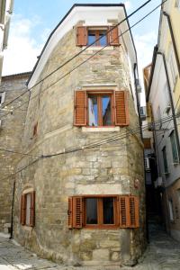 un antiguo edificio de piedra con ventanas con persianas marrones en Apartments ELA en Piran