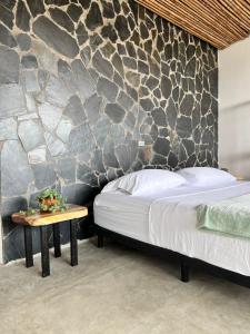 Papagalleros的住宿－Natural Luxury Hotel，一间卧室设有一张床和石墙