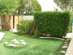 a garden with rocks on the grass and a hedge at studio 66 in Caumont-sur-Durance