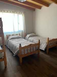 1 dormitorio con 2 camas y ventana en Cabañas PH en Trevelín