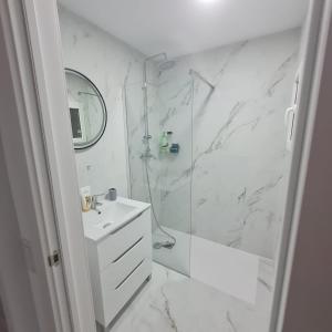 a white bathroom with a shower and a sink at Apartament Lux in Vinarós