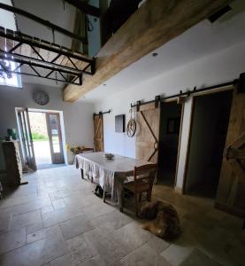 - une salle à manger avec une table et un chien sur le sol dans l'établissement Les naturelles, à Saint-Aubin-de-Locquenay