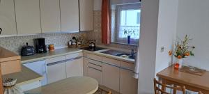 a kitchen with white cabinets and a sink and a table at Retrowohnung Lindenhof Oberndorf in Oberndorf