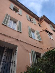 a pink building with green shuttered windows at SUITE CHARABOIS in Saint-Raphaël +3 photos