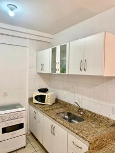 cocina blanca con fregadero y microondas en Flats em Goiania, en Goiânia