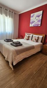 una camera con un grande letto con una parete rossa di Apartamento - Férias Felizes Portimão a Portimão