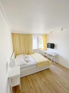 a white bedroom with a bed and a desk at Willa Balticana in Władysławowo
