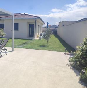 een huis met een patio en een tuin met stoelen bij La Villa d'A-Mours in Mours-Saint-EusÃ¨be