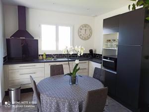 a kitchen with a table and a clock on the wall at La Villa d'A-Mours in Mours-Saint-EusÃ¨be