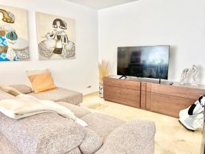 sala de estar con sofá y TV de pantalla plana en Marbella del Mar III Seafront by EaW Homes en Marbella