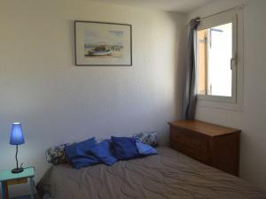 a bedroom with a bed with blue pillows and a window at Appartement Cap d'Agde, 3 pièces, 7 personnes - FR-1-249-44 in Cap d'Agde