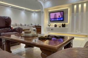 uma sala de estar com uma mesa e uma televisão na parede em Luxury apartment em Fez