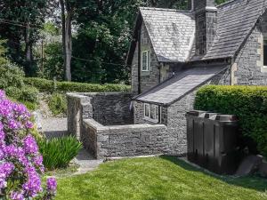 una casa de piedra con una pared de piedra en el patio en Llantysilio Lodge, en Llangollen