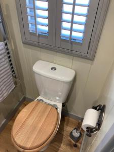 a bathroom with a toilet with a wooden seat and a window at Cotswold shepherd hut with hot tub and sauna Dog friendly in Charlton
