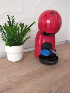 een rood koffiezetapparaat op de vloer naast een plant bij Bonito apartamento con jardín privado en Novo in Novo Sancti Petri