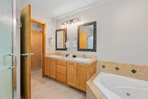 a bathroom with two sinks and a tub and mirrors at Snowstorm Studio at Icicle Village with pool and hot tub in Leavenworth
