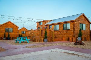 a wooden cabin with a blue picnic table in front of it at The Big Texan - Cabins and Wagons in Amarillo