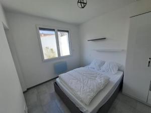 um quarto branco com uma cama e uma janela em Les embruns em Saint-Jean-de-Monts