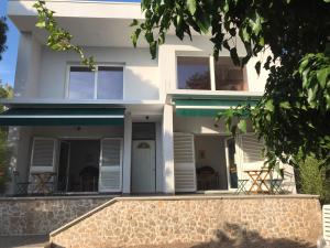 a white house with chairs in front of it at Apartments Mare More in Brodarica