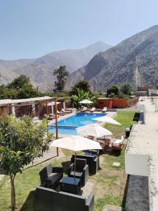 un complejo con una piscina con sombrillas y sillas en HOTEL MAR Y LAGO en Lunahuaná