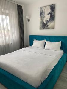 a blue bed with white sheets and pillows at KOA - NorthSide Apartment in Braşov