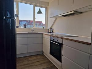 uma cozinha com armários brancos, um lavatório e uma janela em Aarhus Penthouse em Arhus