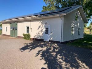 a small white building with a green door at Fin lägenhet mitt på Bjärehalvön in Båstad